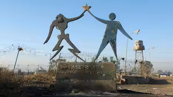 District 9 sign with alien and human figures in a barren landscape