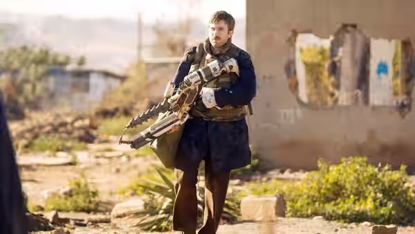 Wikus (Sharlto Copley) carrying a large alien firearm in a derelict area