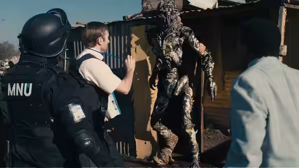 MNU officers confronting a tall alien beside a corrugated metal wall