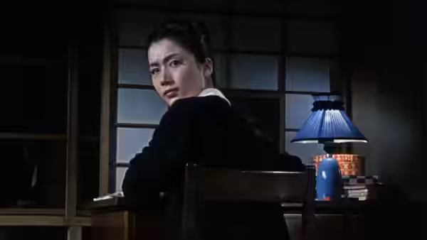 Michiko Hirayama (Shima Iwashita) turns from her desk beneath a blue lamp