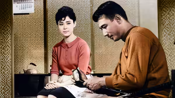 A young woman sits beside a man examining papers at a table