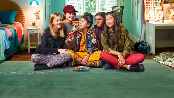 Five friends sit together on a bedroom floor around a board game