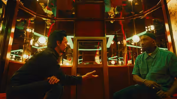 Two men talk across a table in a warmly lit restaurant