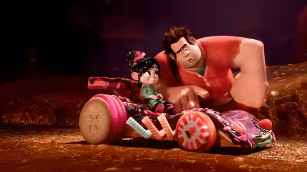Ralph (John C. Reilly) pointing while riding with Vanellope (Sarah Silverman) in a candy car