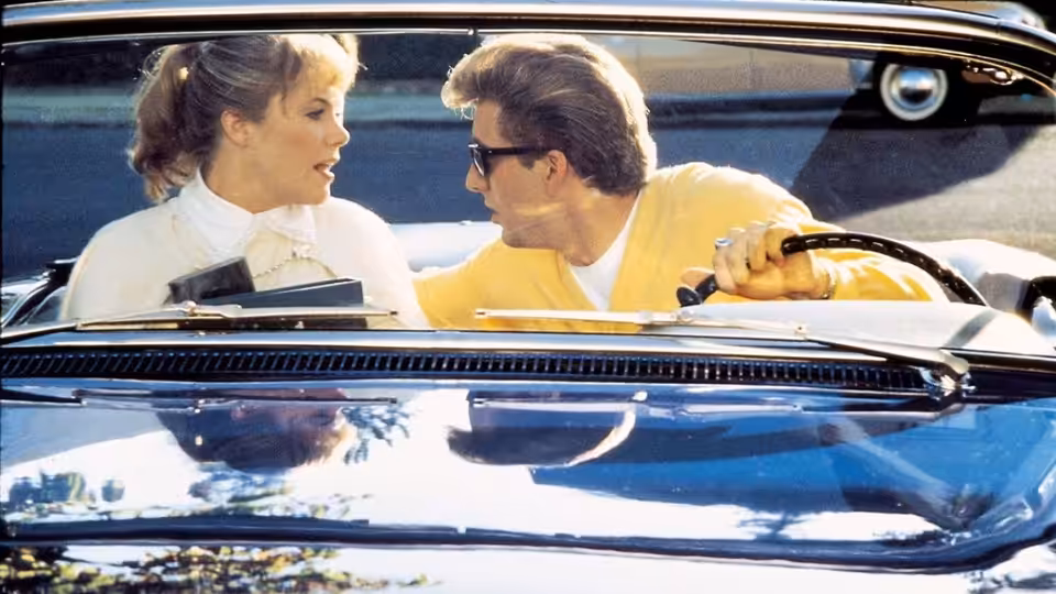 Peggy Sue (Kathleen Turner) and Charlie (Nicolas Cage) chatting in a blue convertible