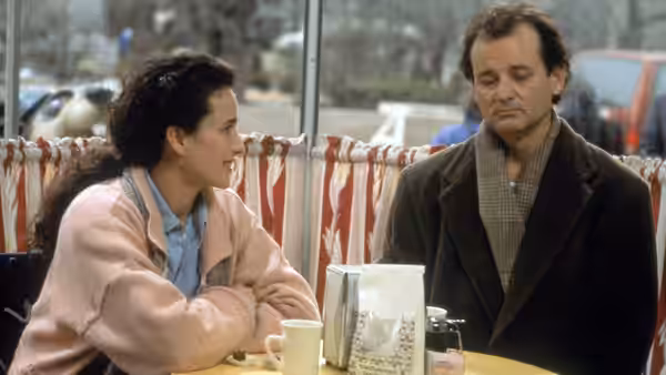 Rita Hanson and Phil Connors seated at a table by large windows