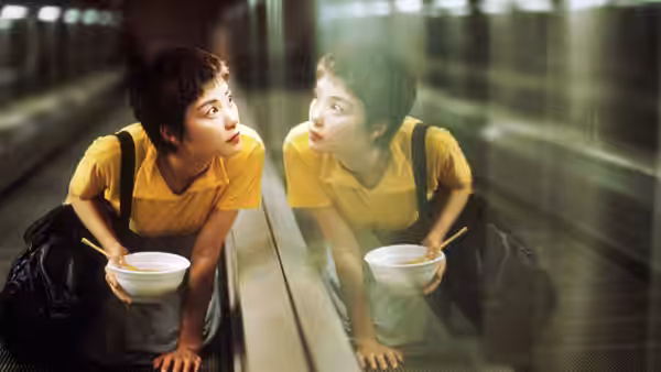 Woman in yellow shirt holding bowl and gazing at her reflection