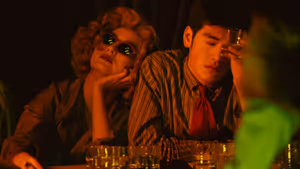 Woman in blonde wig and man in striped shirt at a bar counter