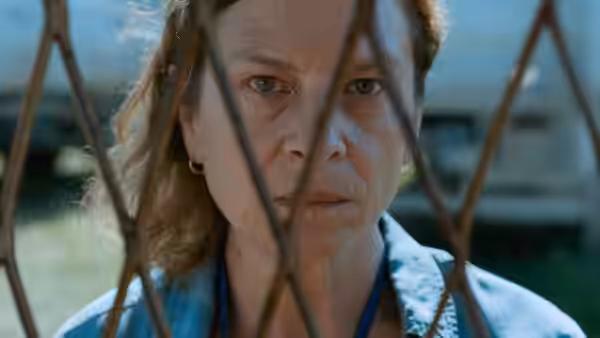 Aïda (Jasna Đuričić) looks through a metal fence