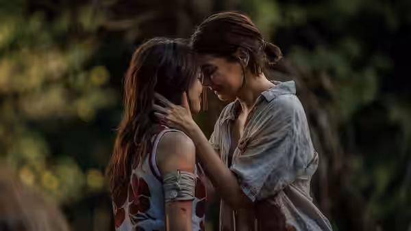 A woman cradles another woman's face as they stand close together outdoors
