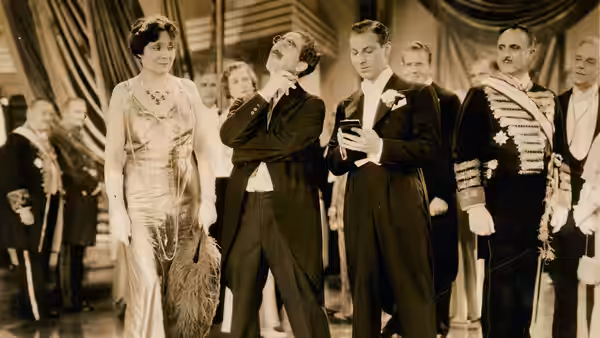 A woman in a beaded gown stands among men in formal and military attire at an event