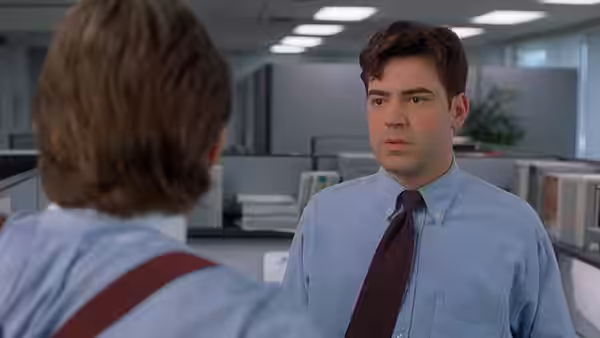 two men standing face to face in an open plan office space