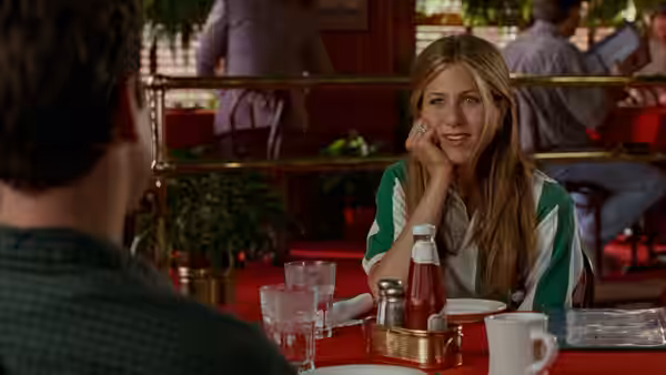 Joanna (Jennifer Aniston) seated at a restaurant table during conversation