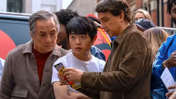 Mr. Han (Jackie Chan) and Li Fong examine a card with another man