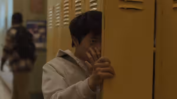 Li Fong peeks around a school locker