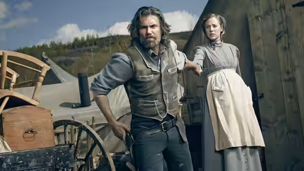 Cullen Bohannan stands beside Lily Bell on a train platform