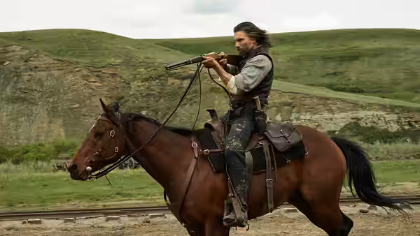 Cullen Bohannan (Anson Mount) rides a horse across open grassland, holding a rifle