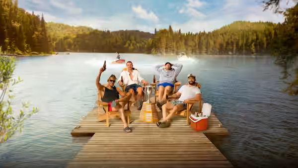 Four men sit in folding chairs on a wooden dock extending into a lake