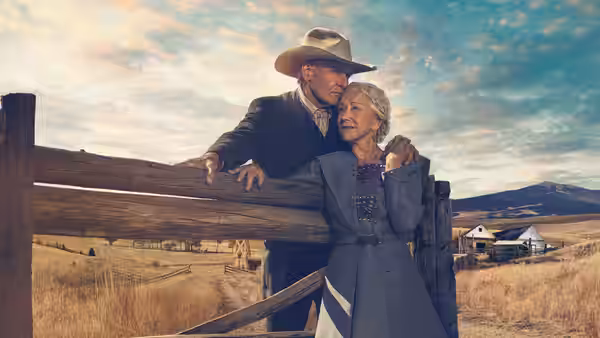 Jacob Dutton (Harrison Ford) embraces Cara Dutton (Helen Mirren) beside a ranch fence