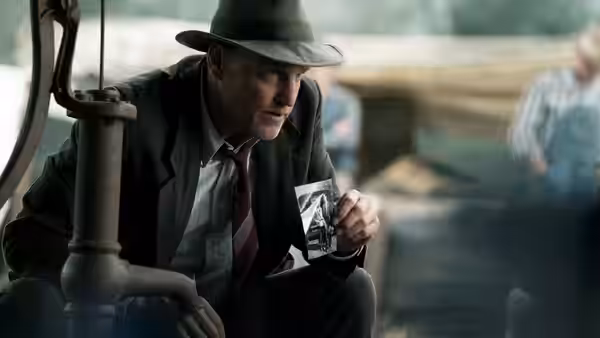 Frank Hamer (Kevin Costner) crouches in a car, holding up his badge