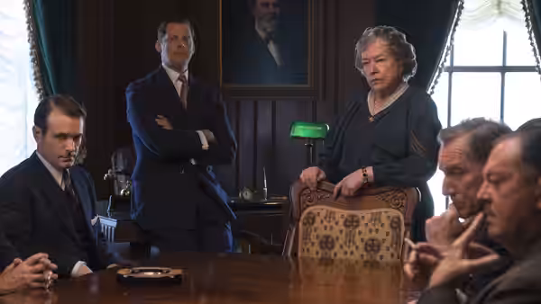 Ma Ferguson (Kathy Bates) stands behind a chair as officials gather around a table
