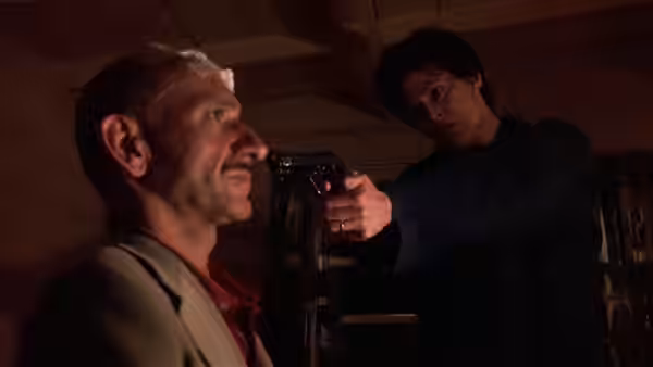 Paulina Escobar (Sigourney Weaver) aims a revolver at a seated man in a dim room