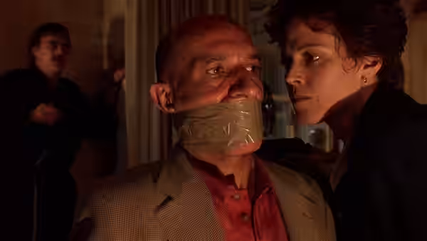 Paulina Escobar (Sigourney Weaver) confronts a gagged man indoors while another man watches