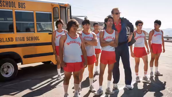 Jim White (Kevin Costner) stands with his team beside a school bus