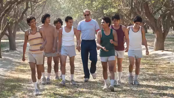 Jim White (Kevin Costner) walks with McFarland runners beneath a tree-lined path