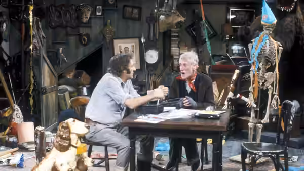Harold (Harry H. Corbett) and Albert (Wilfrid Brambell) sit at a cluttered table
