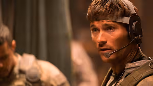 A soldier wearing a headset listens intently inside the outpost