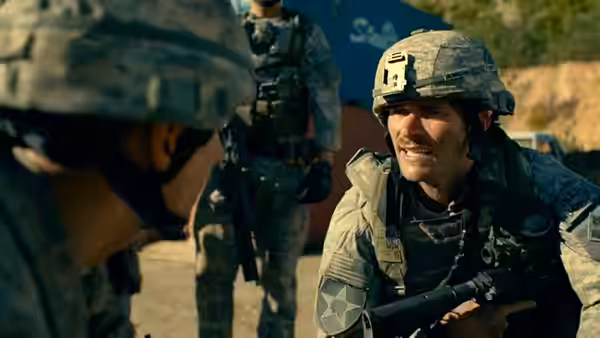 Clint Romesha (Scott Eastwood) crouches beside a fellow soldier at the outpost
