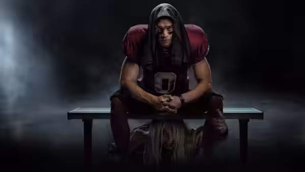 Cam sits hunched on a bench as a woman hangs upside down beneath it