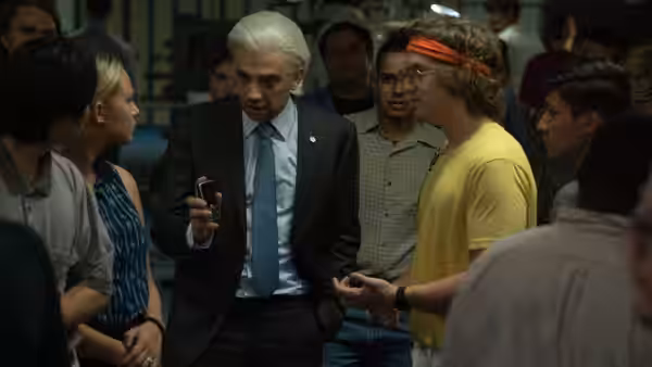 Doug (Matt Johnson) talks with a suited executive in a crowded office