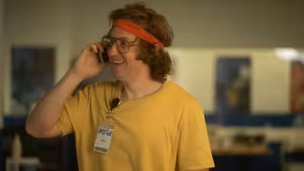 Doug (Matt Johnson) smiles while holding a phone to his ear