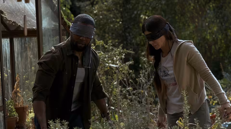 Tom (Trevante Rhodes) and Malorie (Sandra Bullock), blindfolded, tend plants outside