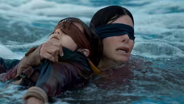 Malorie (Sandra Bullock) pulls a child through rough water while both wear blindfolds