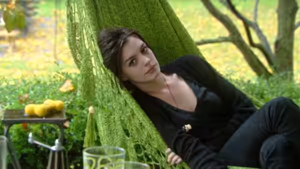 Kym (Anne Hathaway) reclining in a green hammock in a garden