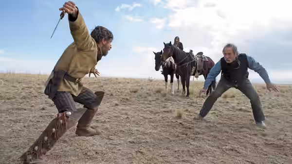 Two men square off in a field as a woman watches from horseback