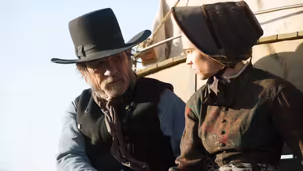George Briggs (Tommy Lee Jones) sits beside Mary Bee Cuddy (Hilary Swank) on a wagon