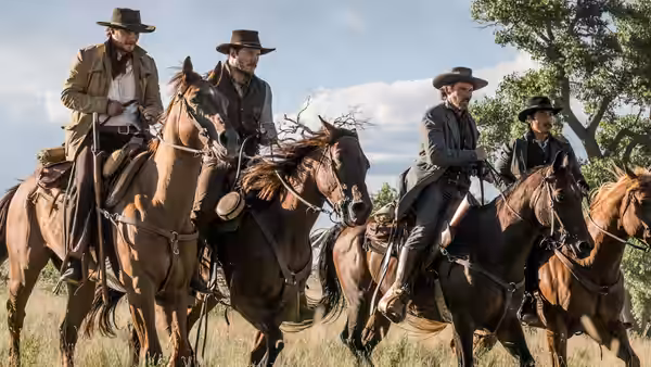 Cowboys ride horses together across open countryside