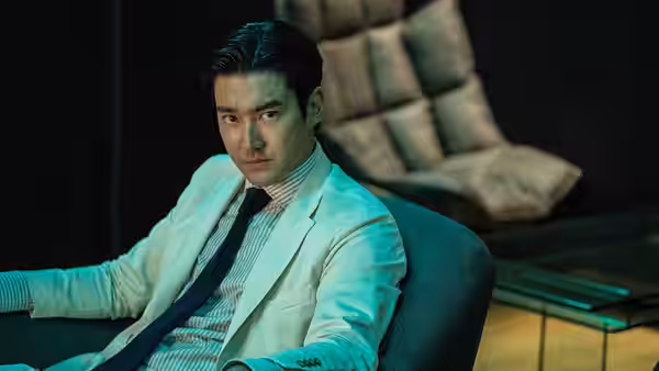 Kim Myeong-gil (Park Seong-ung) sits in a white suit in a modern office