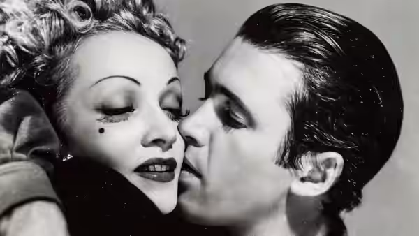 Frenchy (Marlene Dietrich) leans in to kiss a dark-haired man