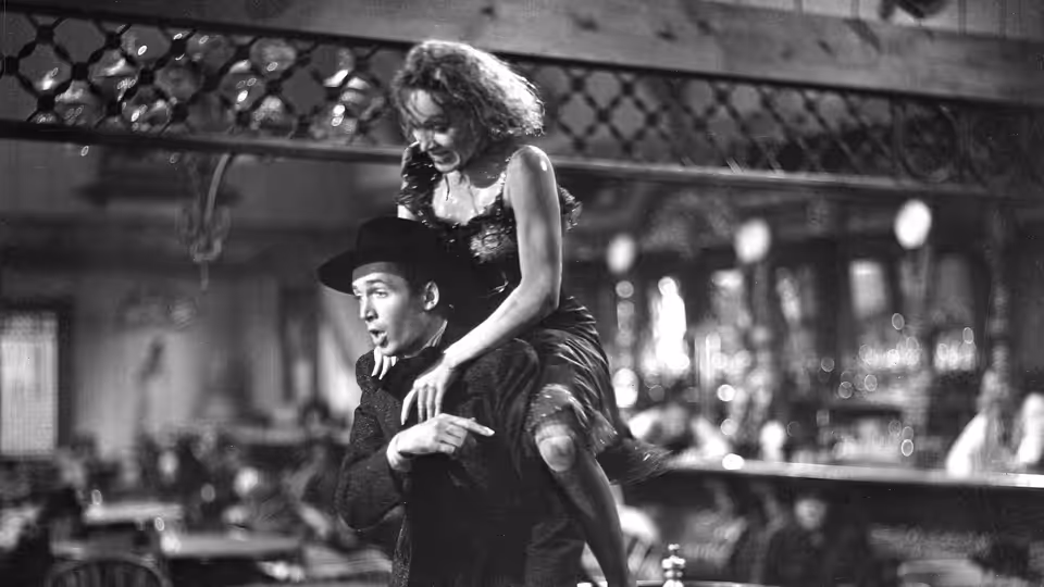 Frenchy (Marlene Dietrich) sits astride Tom Destry Jr. (James Stewart) in the saloon