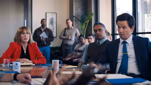 Brad (Mark Wahlberg) and a woman in a red blazer sit at a meeting table