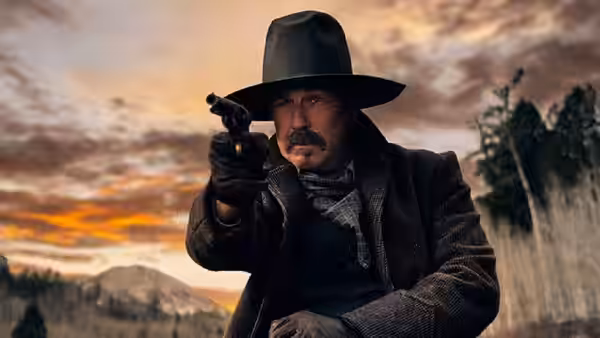 Hayes Ellison (Kevin Costner) aims a pistol across the open range at dusk