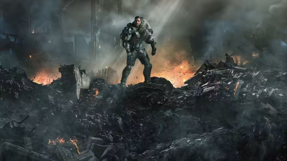 Master Chief (Pablo Schreiber) stands on a mound of rubble amid a burning battlefield
