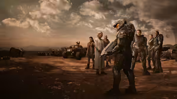 Master Chief (Pablo Schreiber) faces a group of people beside vehicles on an open plain