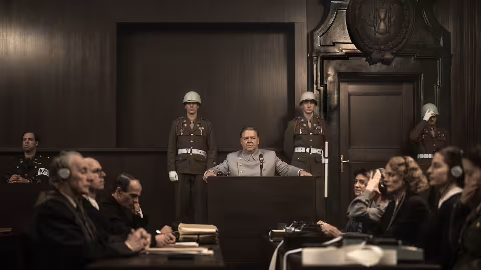 A judge presides over a courtroom as uniformed guards stand behind him