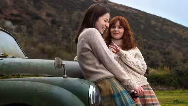 Dolours Price (Lola Petticrew) and Marian Price (Hazel Doupe) embrace beside a parked car